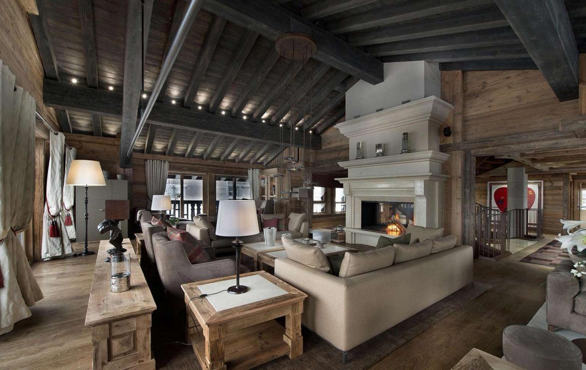 kings-avenue-luxury-chalet-courchevel-001-living-room-with-open-fireplace-front-view