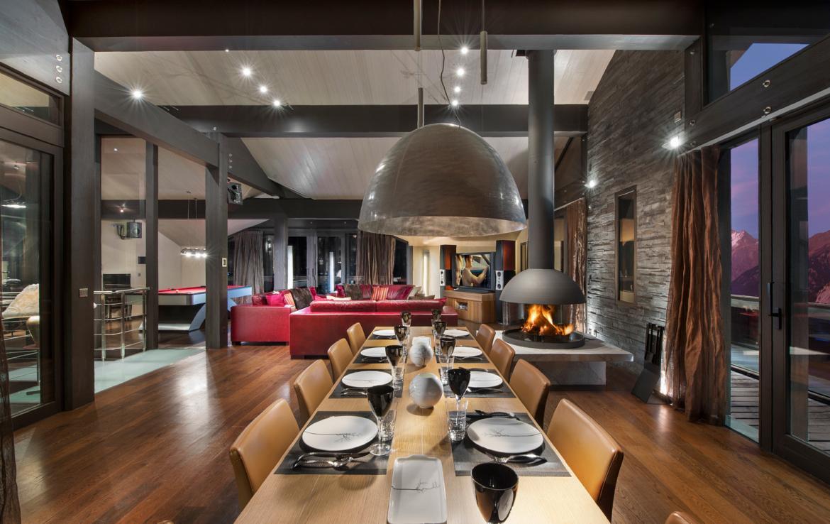 kings-avenue-luxury-chalet-courchevel-003-living-area-with-dining-table-and-open-fireplace