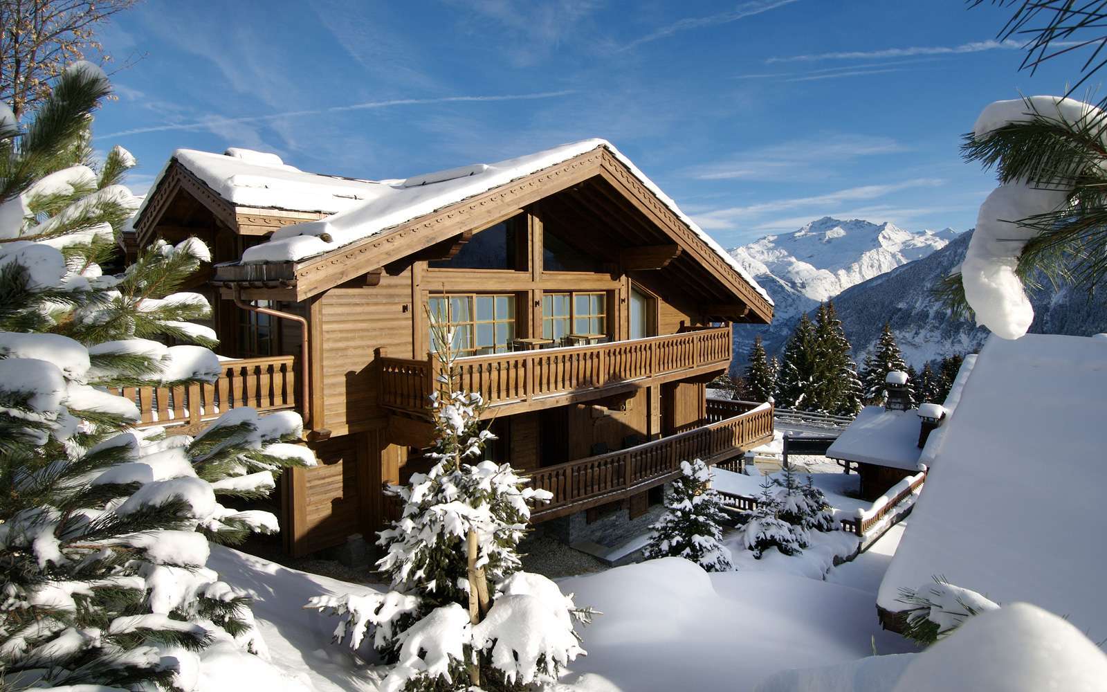 kings-avenue-luxury-chalet-courchevel-004-vista-frontal-exterior-con-nieve-y-cielo-azul