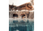 Ultima-Crans-Montana,-Jumping-into-a-Heated-Outdoor-Pool-with-Chalet-in-the-Background